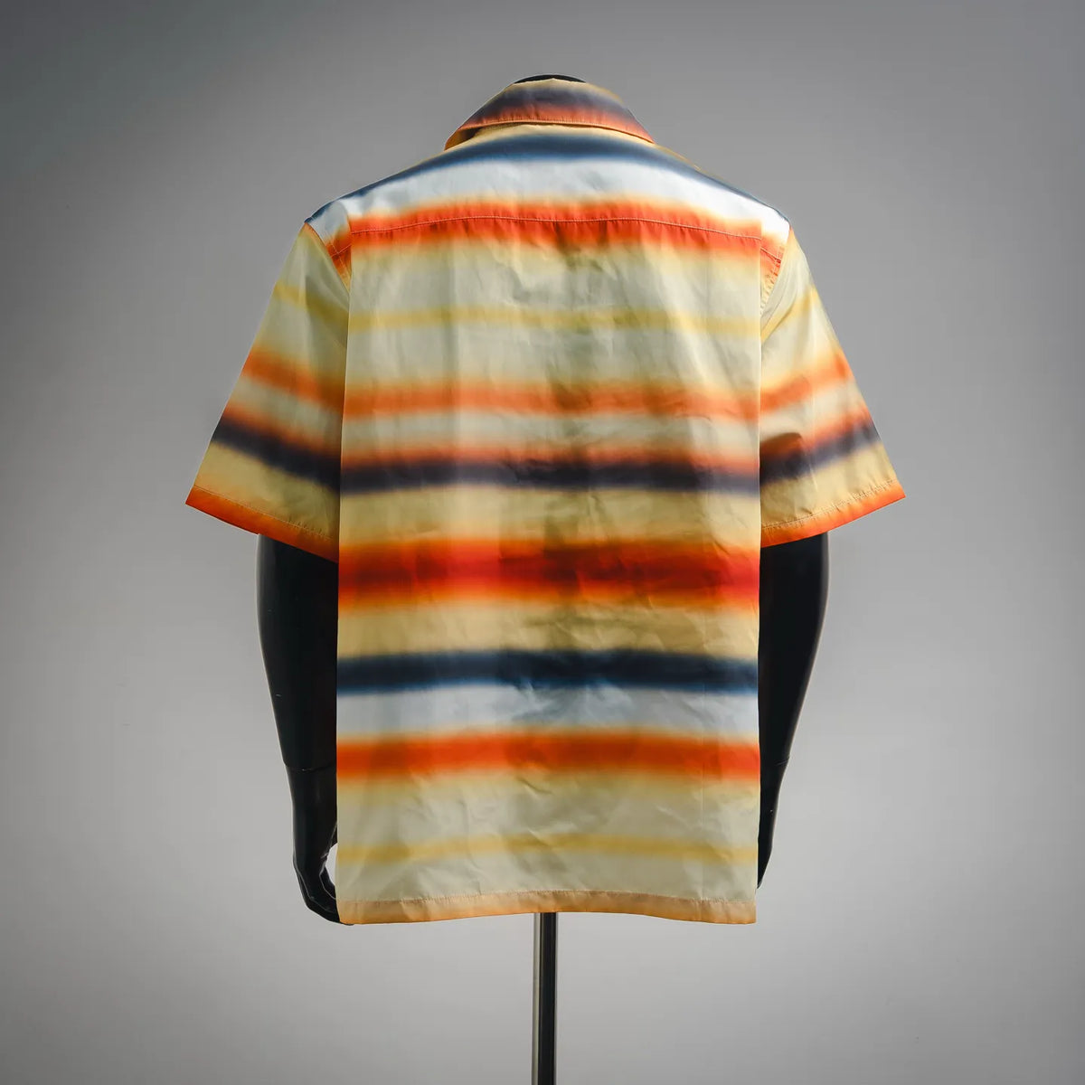 Back view of short-sleeve button-up shirt with orange, blue, and cream stripes