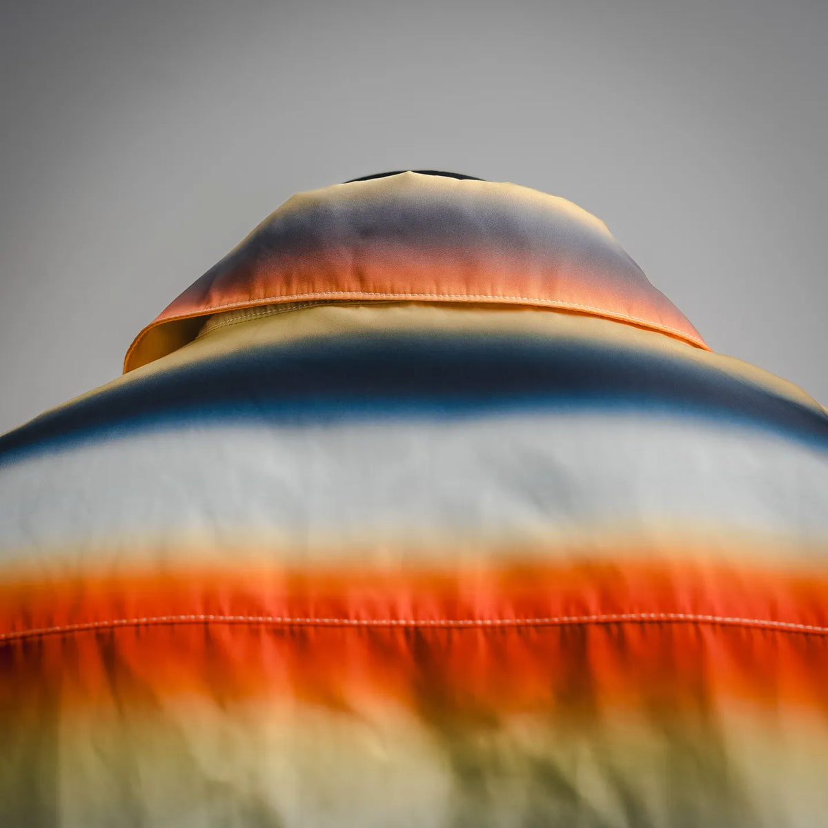 Collar and shoulder of short-sleeve shirt with orange, blue, and cream stripes