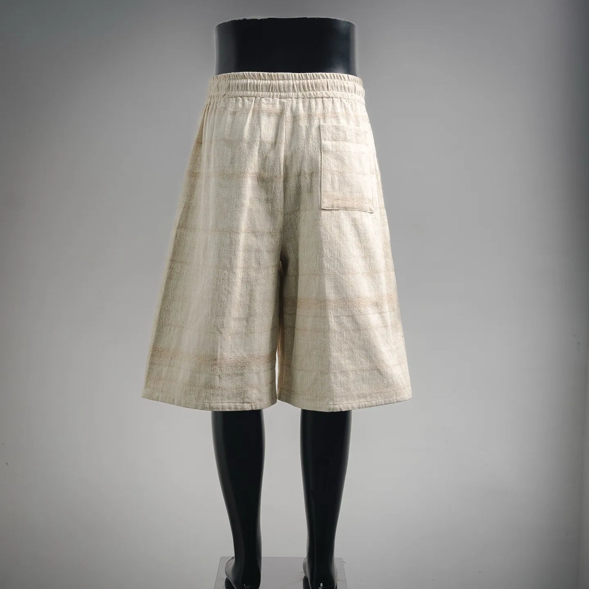Off-white linen shorts with elastic waistband, pleated front, and side pockets