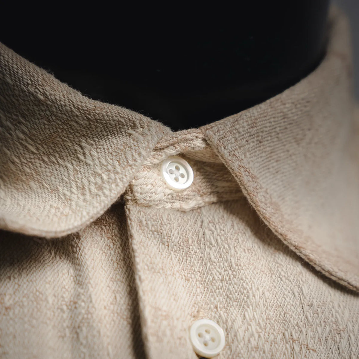 Beige shirt collar with white buttons and button placket.
