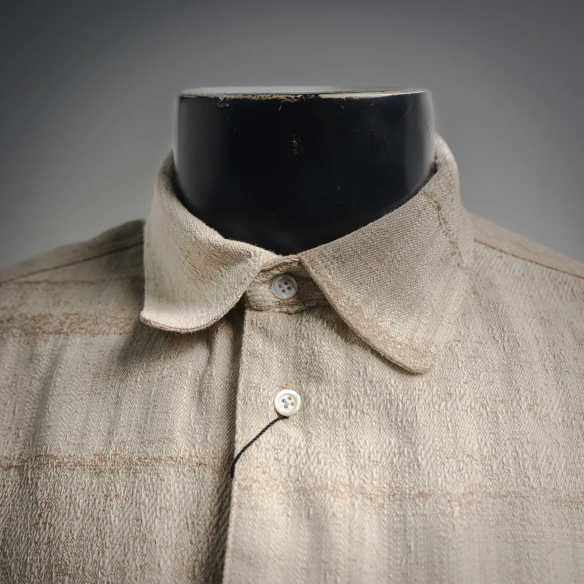 Beige long-sleeve shirt neckline with pointed collar and two-button placket.
