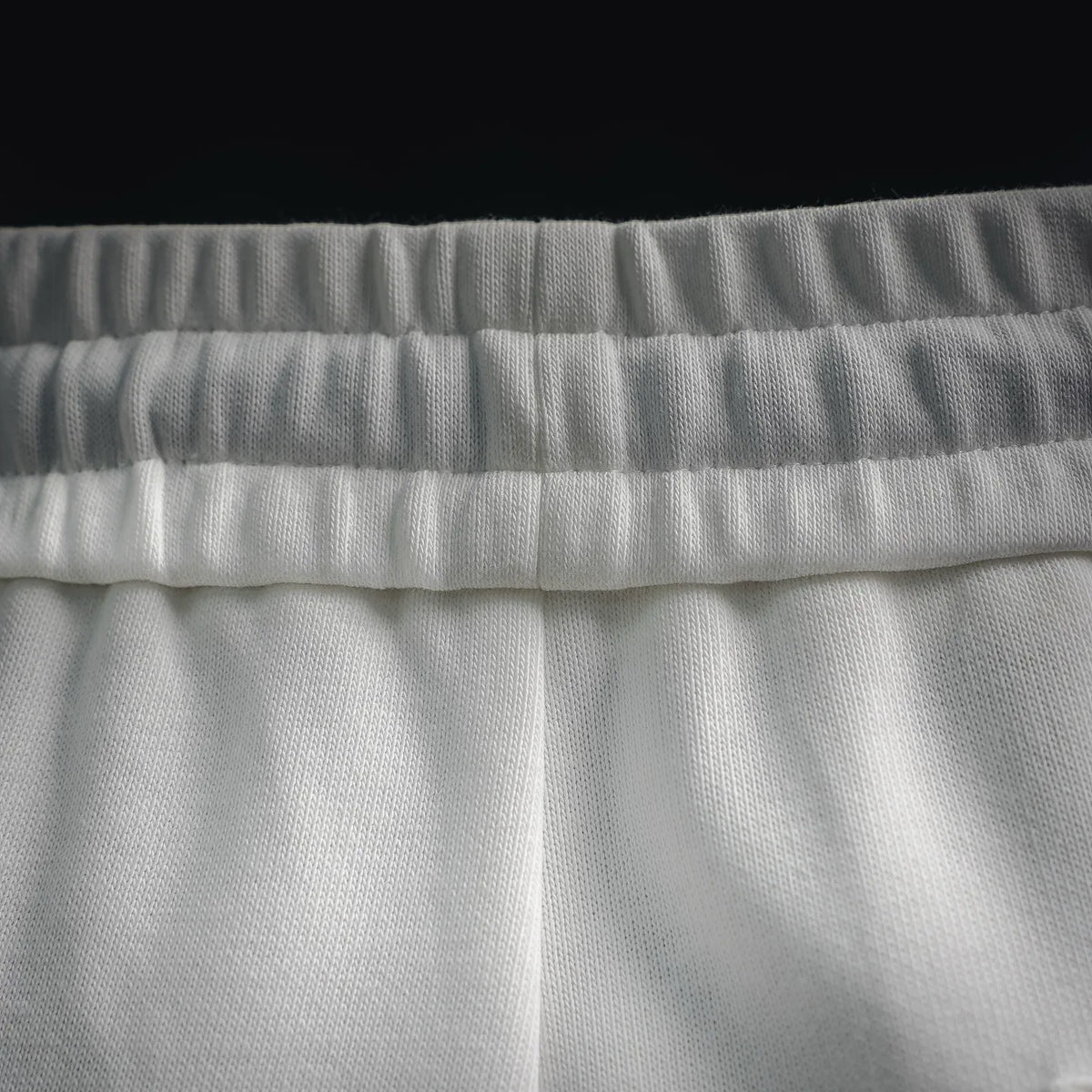 White shorts fabric close-up showing waistband texture and seams