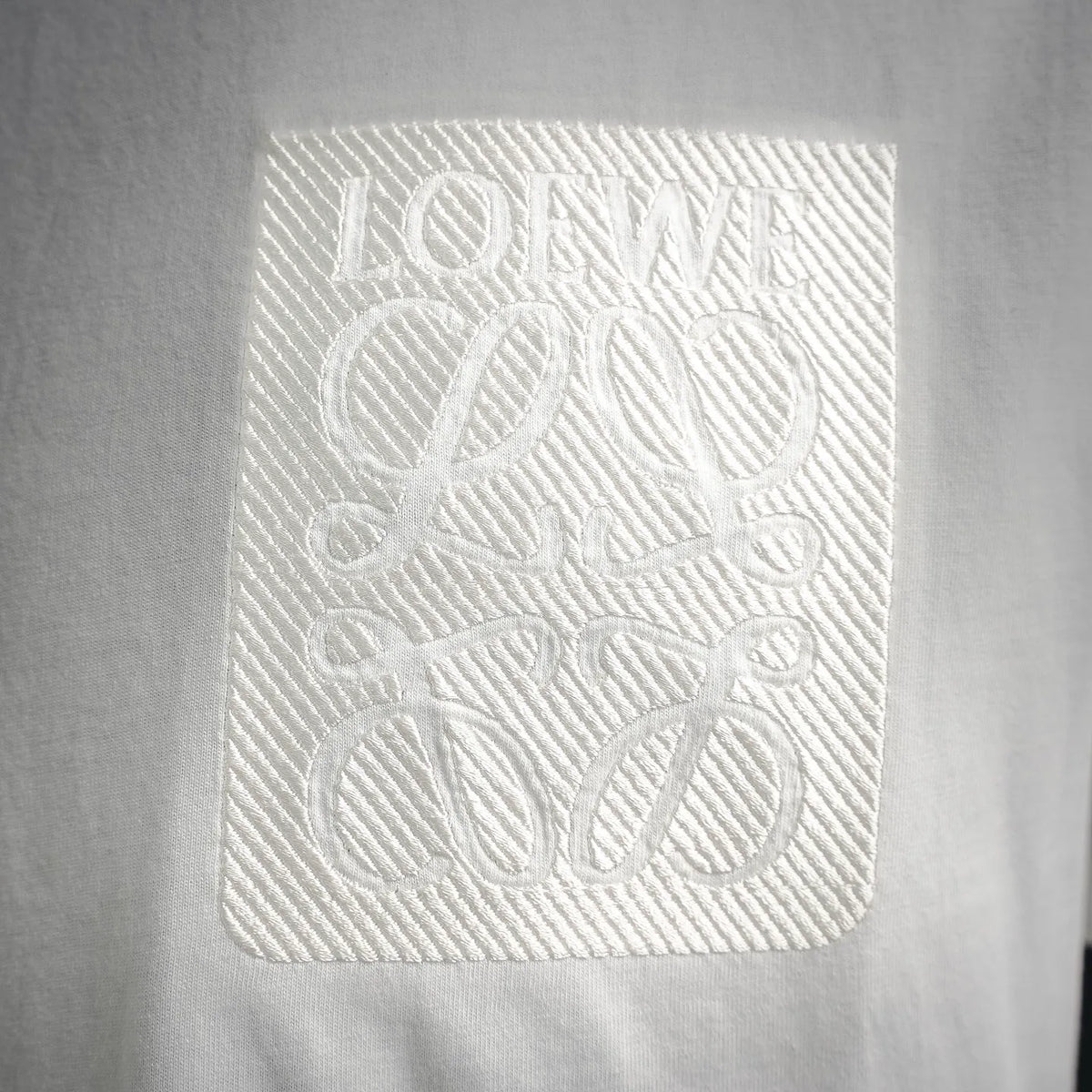 Embossed LOEWE logo patch on white T-shirt fabric