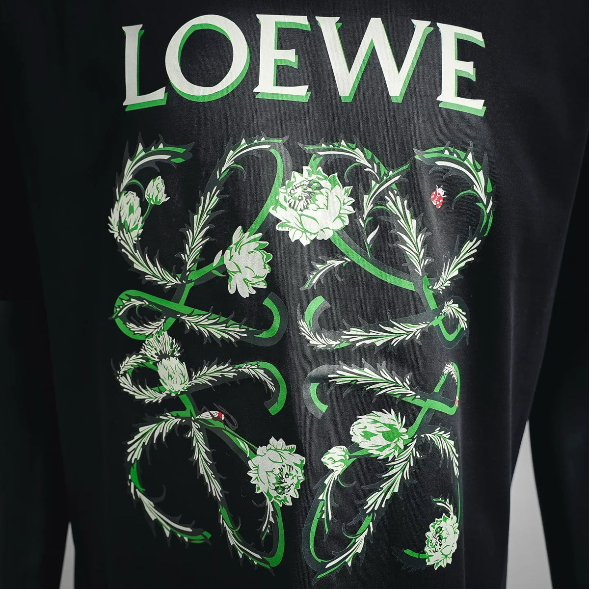 Close-up of LOEWE front graphic: green floral design on dark shirt