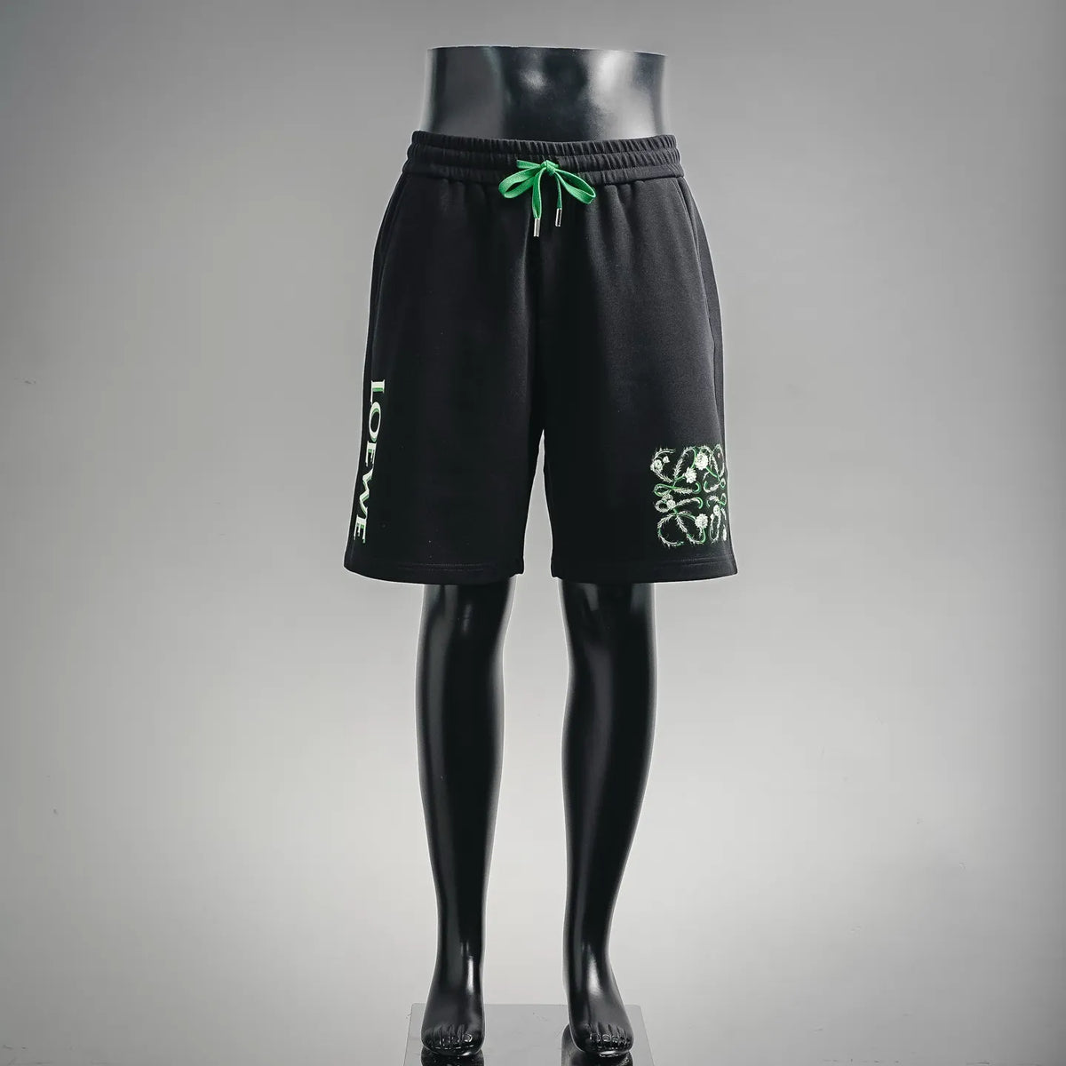 Black LOEWE shorts-style pants with green drawstring and graphic logo patch