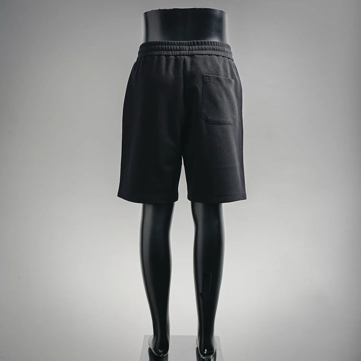 Black shorts-style pants with elastic waistband and side pocket, back view