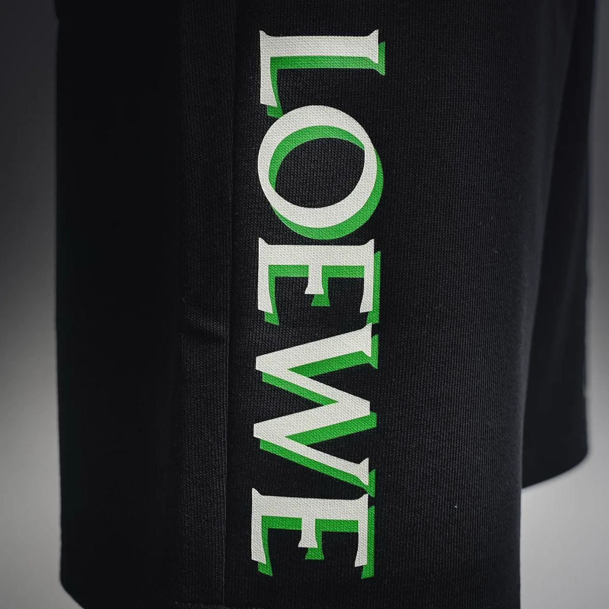 Green and white logo graphic on black shorts-style pants