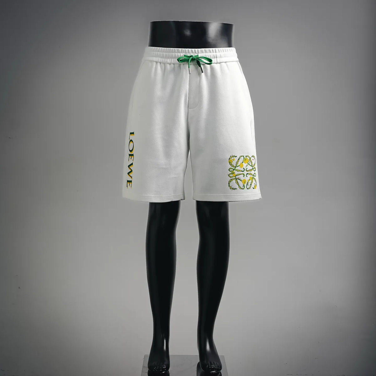 White drawstring shorts with green trim and multicolor logo graphic on the leg