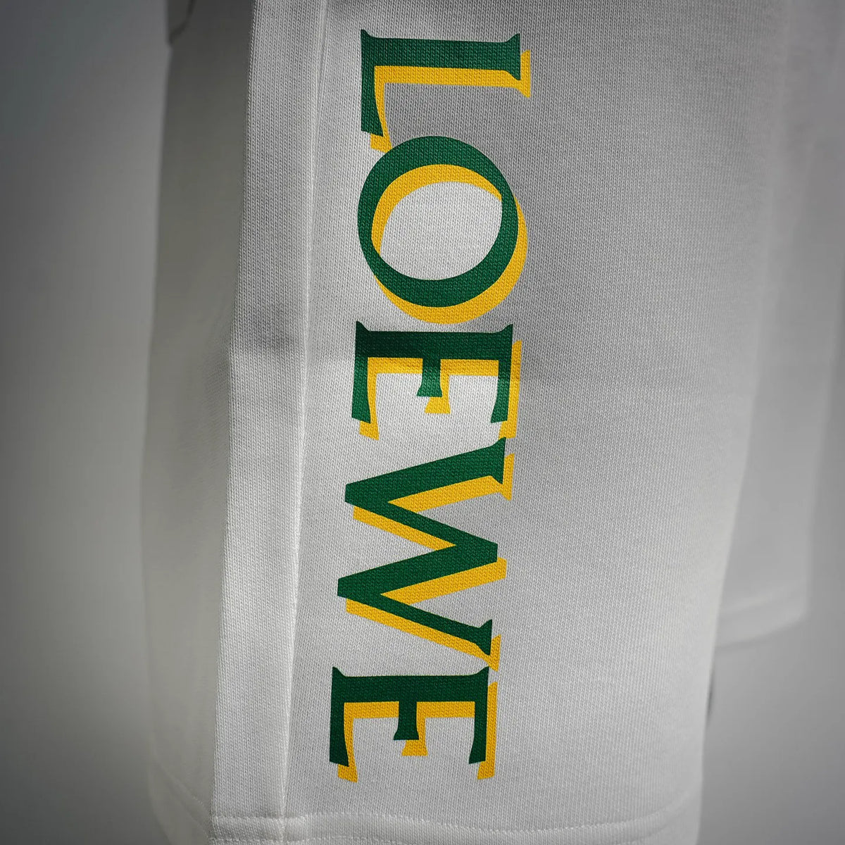 White shorts with vertical multicolor LOEWE logo print in green and yellow