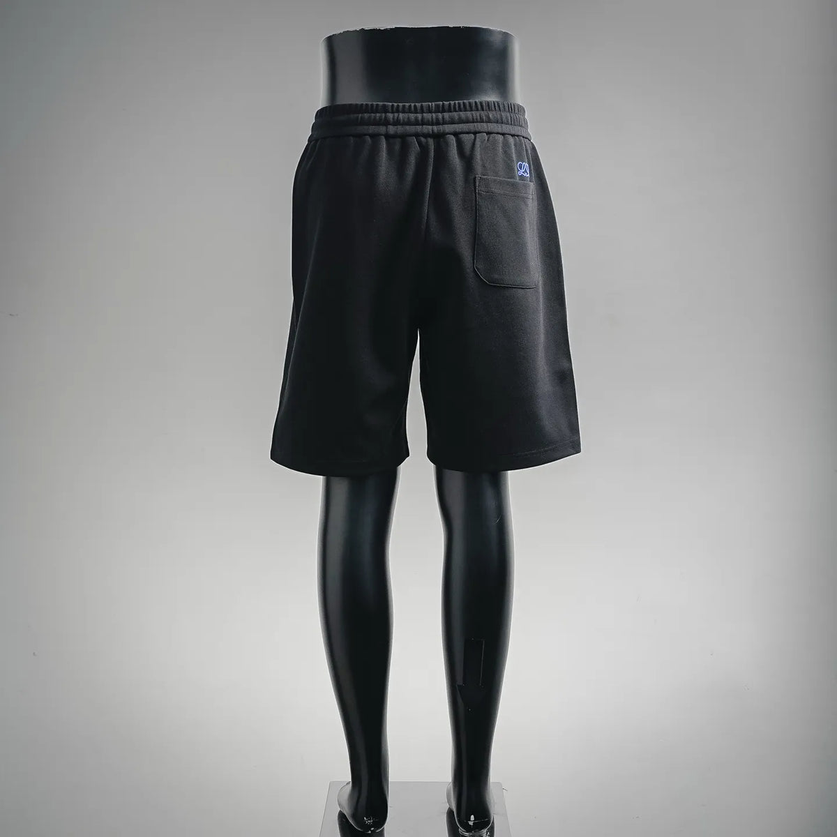 Black drawstring shorts with elastic waistband and side pocket, blue logo detail