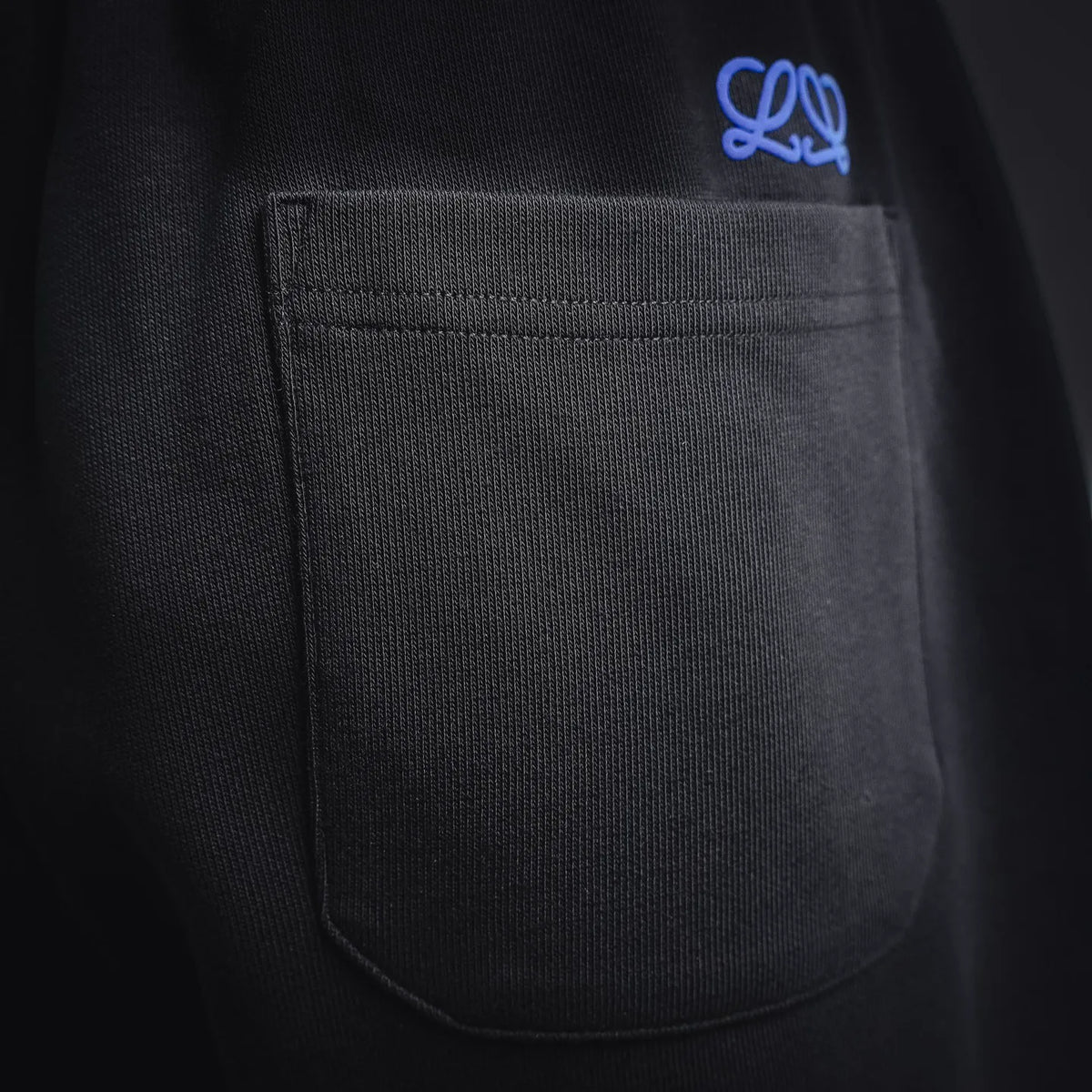 Black shorts pocket with curved opening and small blue embroidered logo