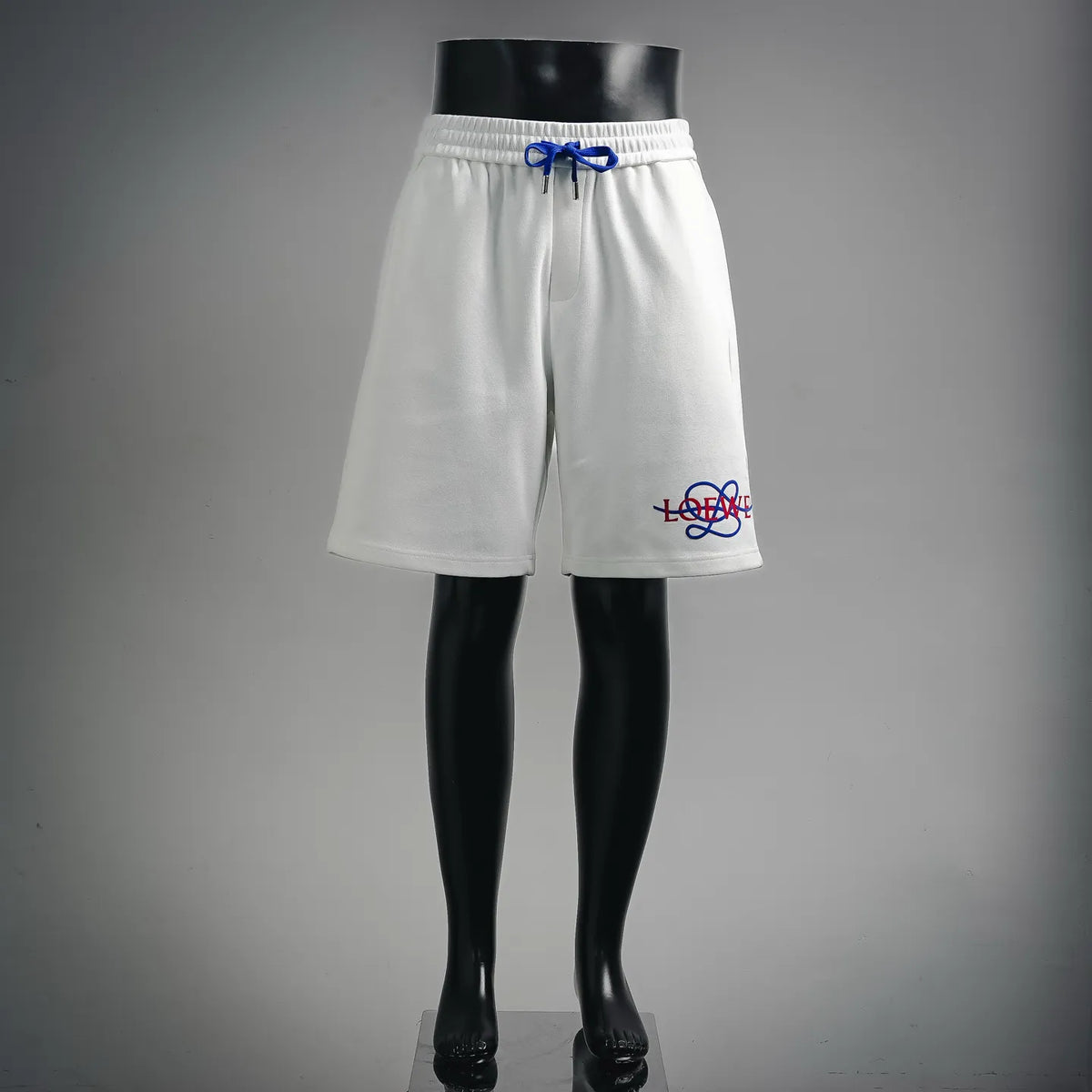White LOEWE drawstring shorts on mannequin, front view, blue drawcord, logo detail.