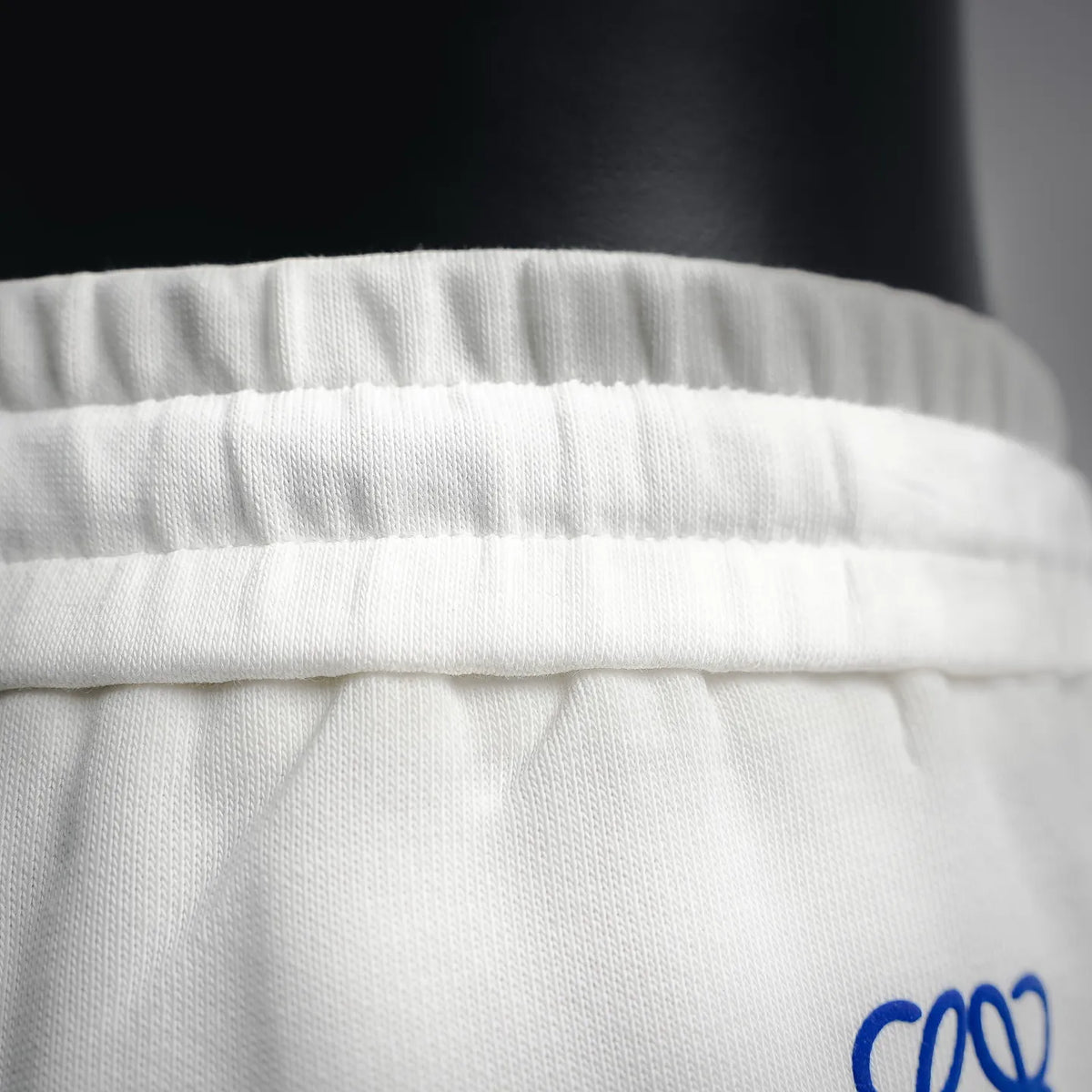 White LOEWE waistband close-up showing elastic gathers and knit fabric texture.