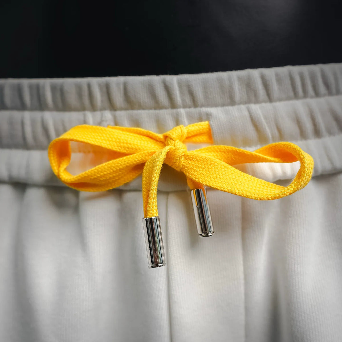 White LOEWE shorts with bright yellow drawstring and metal aglets