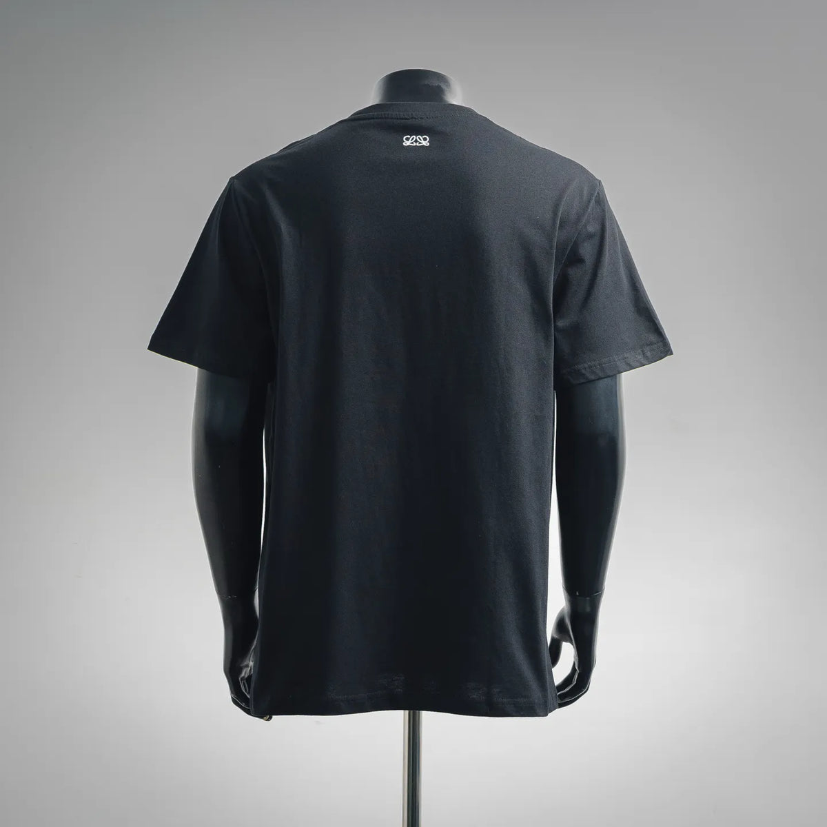 Black crewneck T-shirt back view with small white logo near neckline