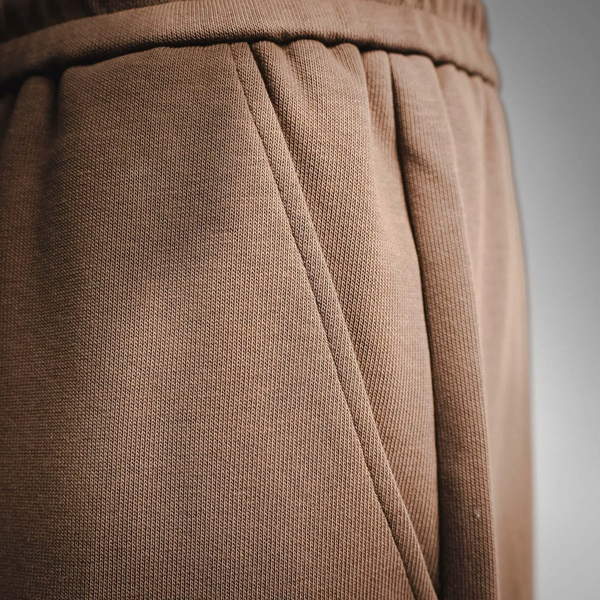 Tan shorts with stitched waistband seam and smooth jersey knit texture