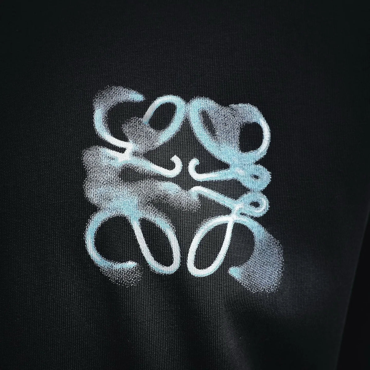 Close-up of light-blue embroidered emblem on black short-sleeve t-shirt