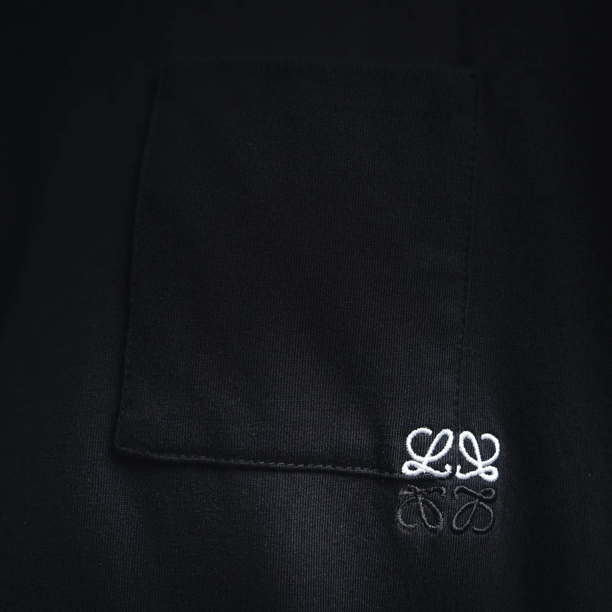 Black T-shirt pocket with small white embroidered logo