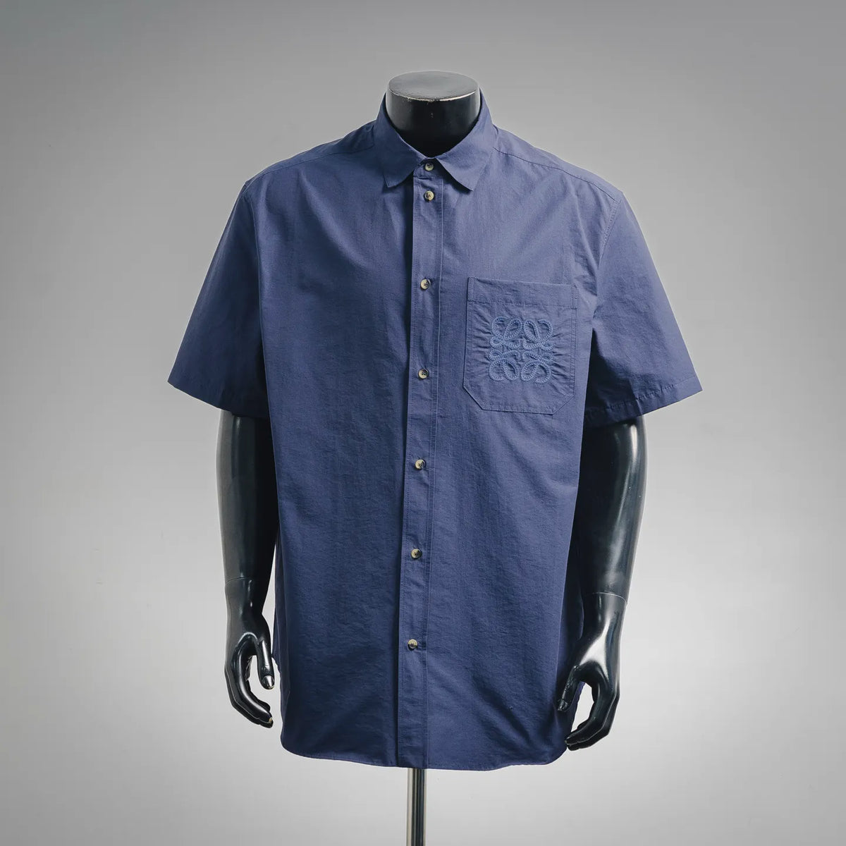 Blue short-sleeve button-up shirt with pointed collar and front button placket.