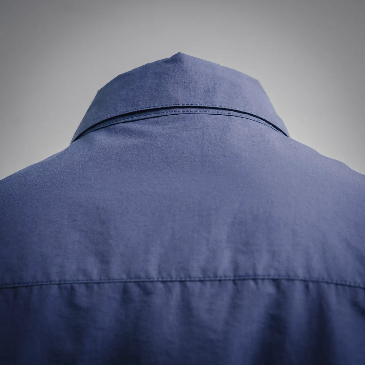 Back collar area of blue short-sleeve button-up shirt with stitched seam detail.