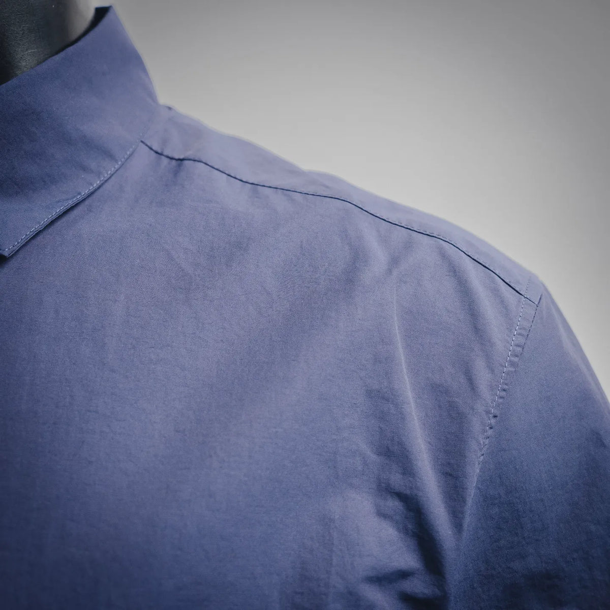 Shoulder and sleeve of blue short-sleeve button-up shirt with neat stitching.