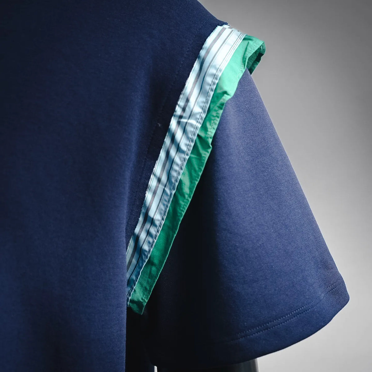 Dark navy T-shirt with green-and-white striped trim at sleeve edge