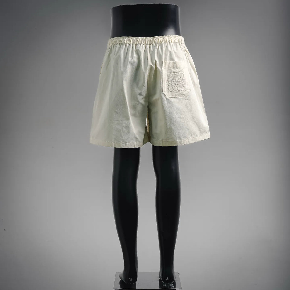 Cream cotton shorts on mannequin, elastic waistband and wide hem.