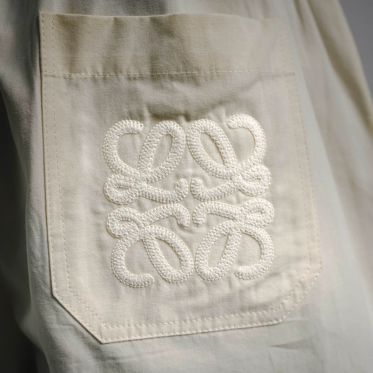 Cream cotton shorts with decorative white stitched logo on front pocket.