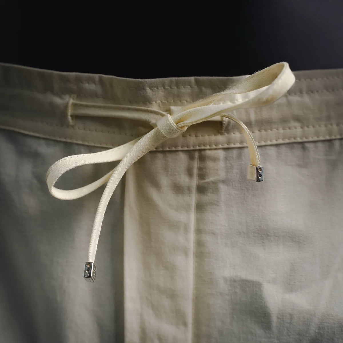 Cream cotton shorts with tie drawstring and button adjuster at waistband.