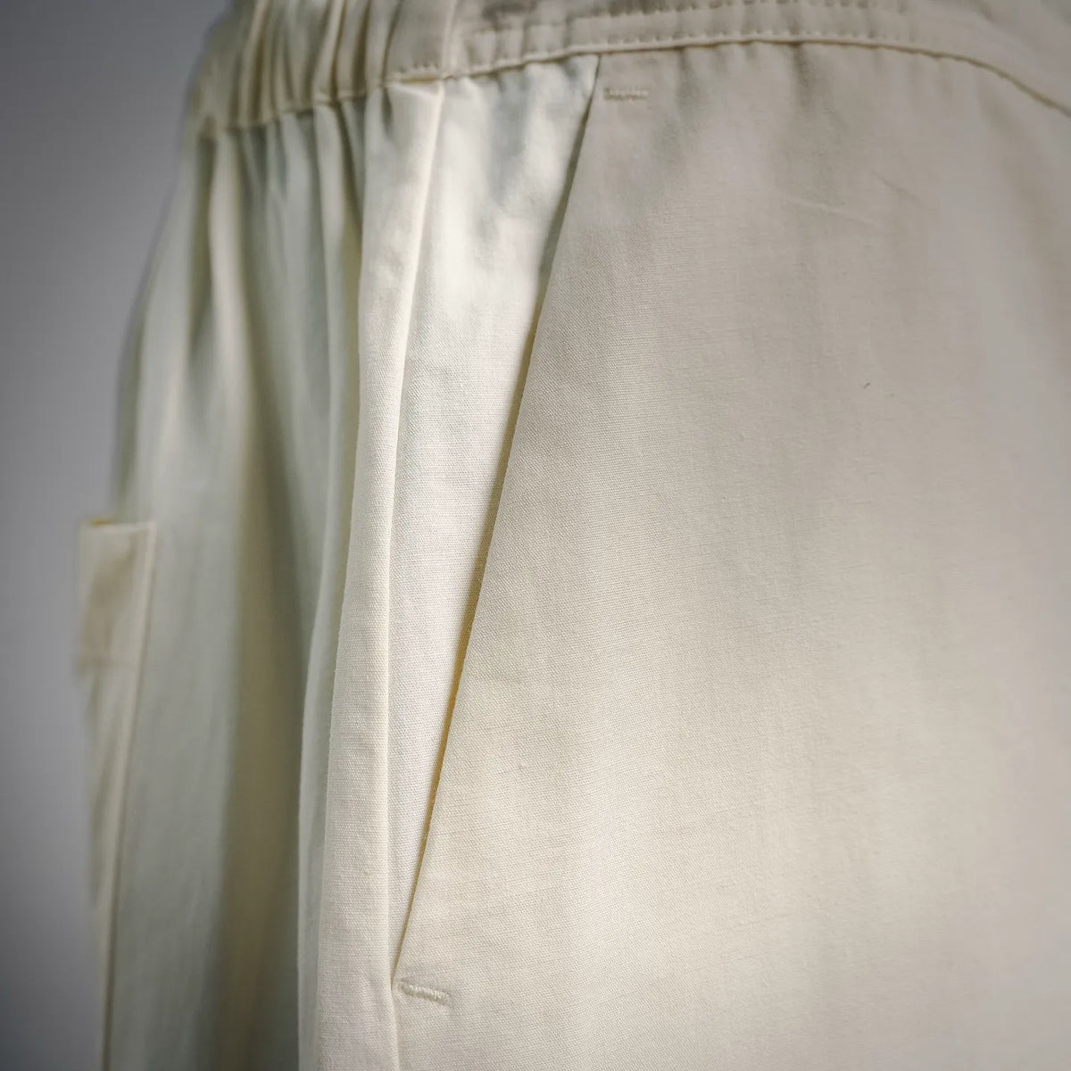 Cream cotton shorts with relaxed drape and stitched side panels.