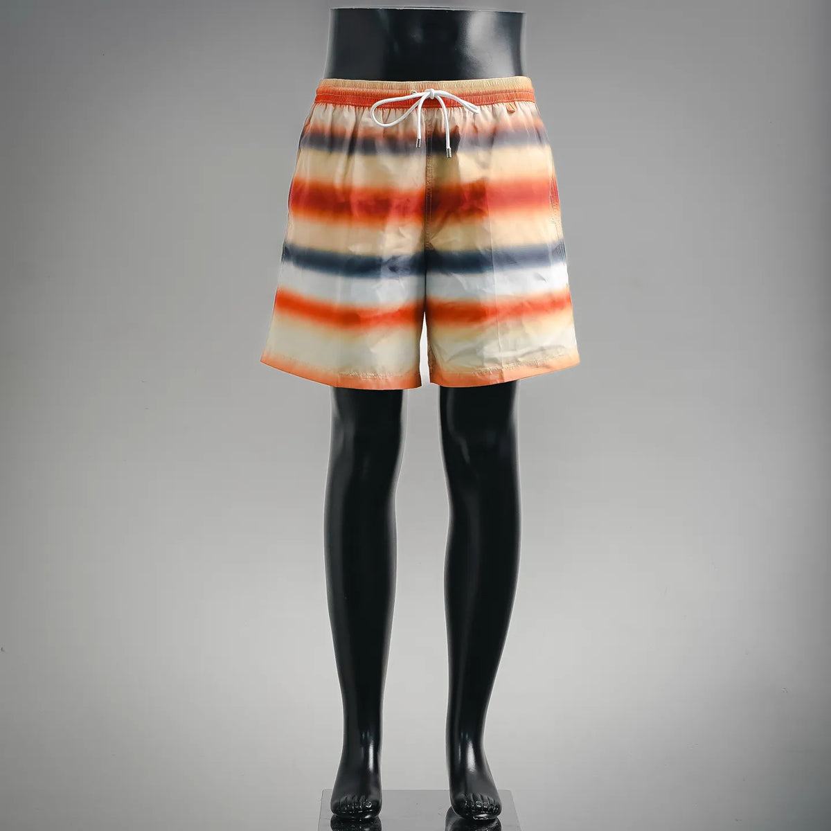 Tie-dye swim shorts with orange, cream, and blue stripes, elastic drawstring waist