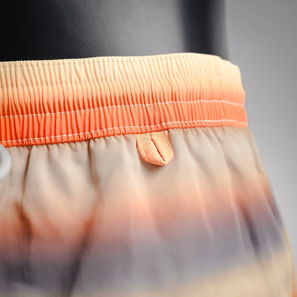 Elastic waistband of tie-dye swim shorts in orange and cream gradient