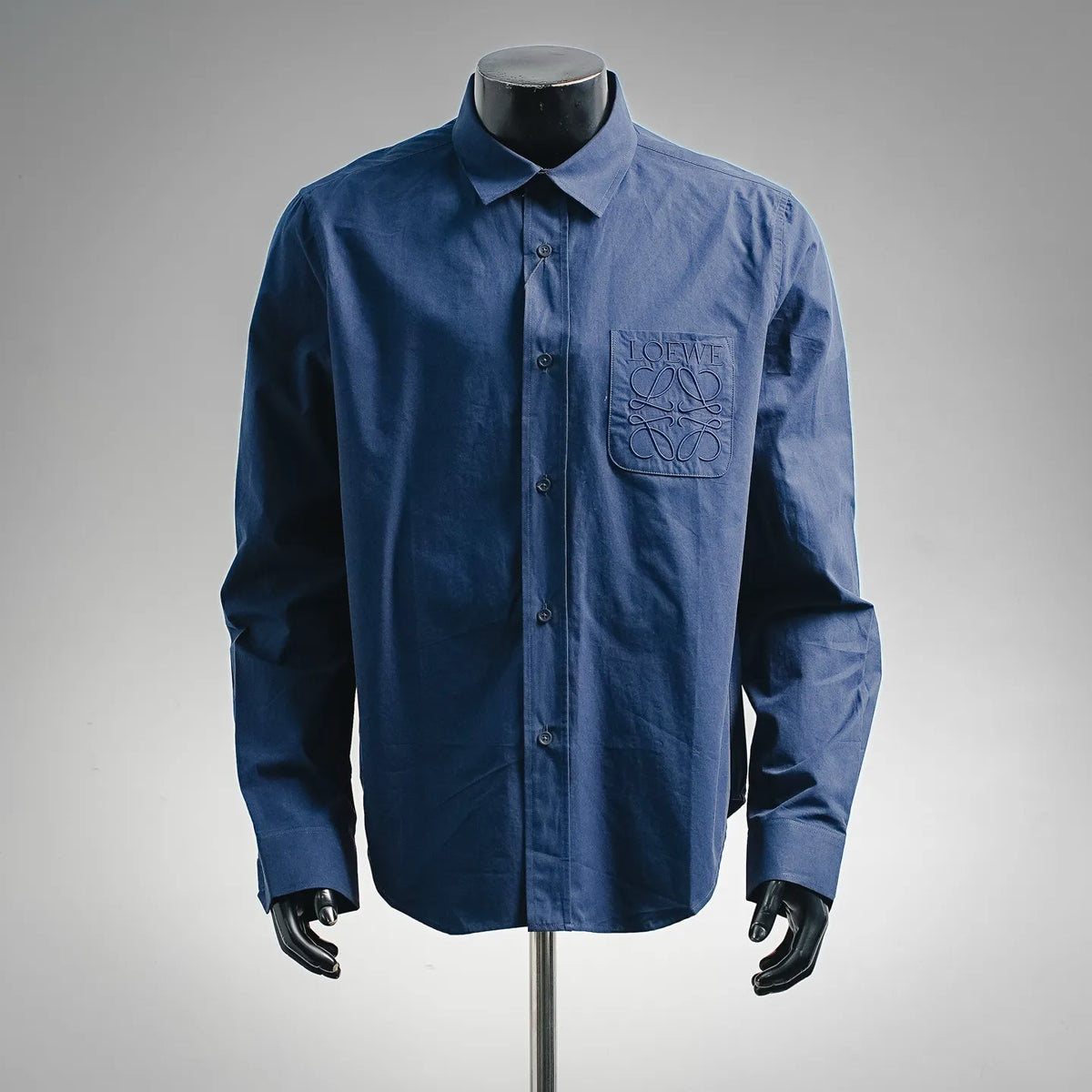 Long-sleeve button-up shirt, blue with chest logo patch and button front.