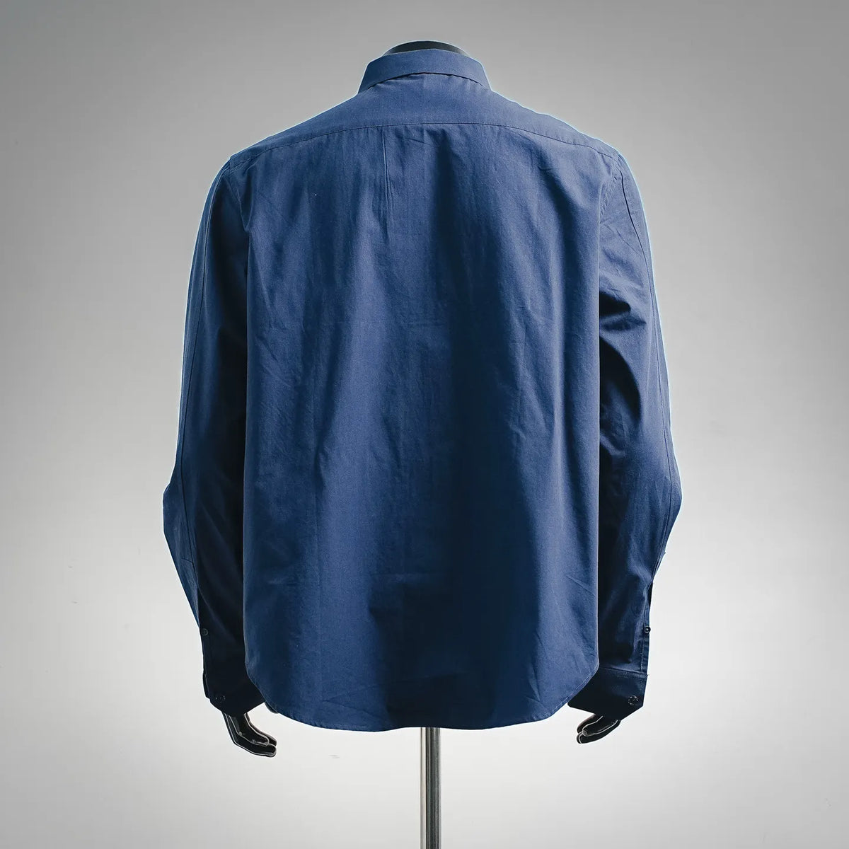 Long-sleeve blue button-up shirt, back view with center pleat.