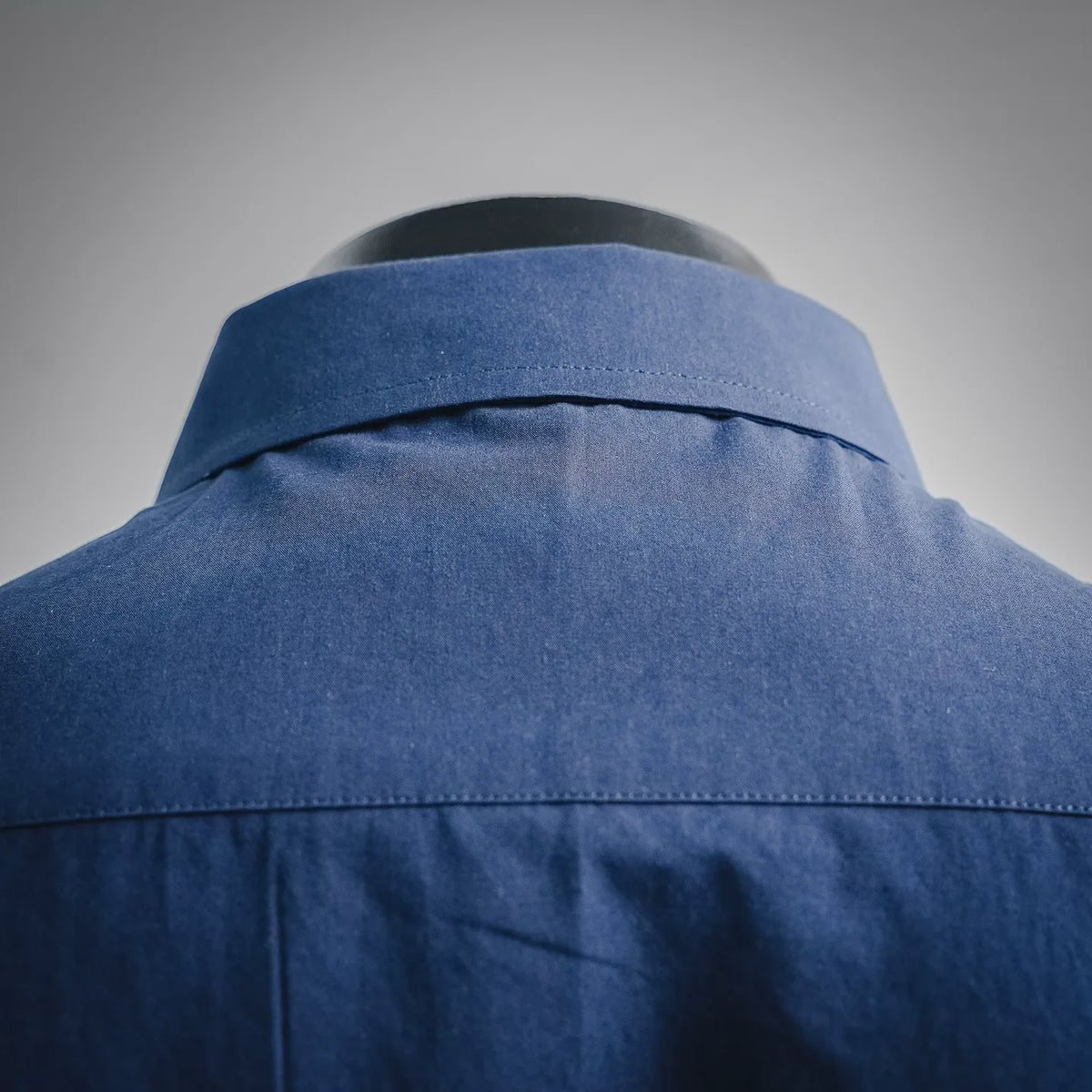 Blue button-up shirt collar and upper back yoke seam detail.