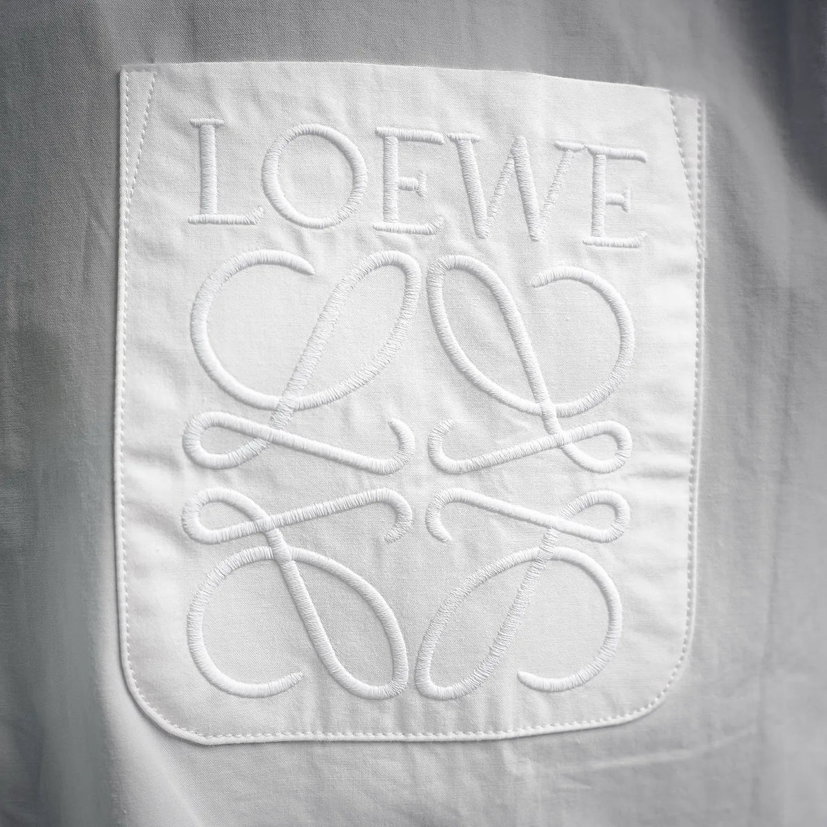 White LOEWE embroidered logo patch on front of button-up shirt