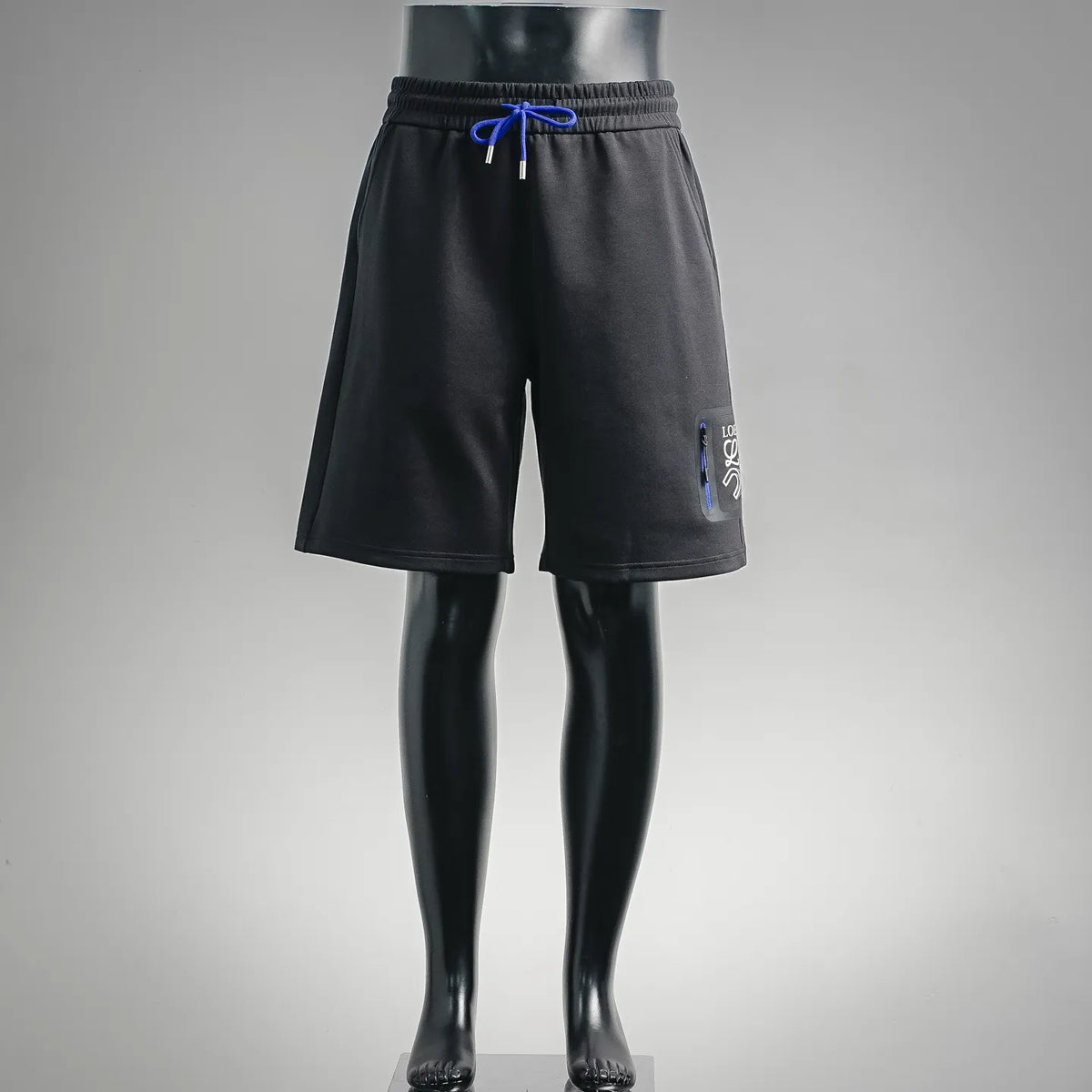 Black drawstring shorts with elastic waistband, side logo patch, relaxed knee-length fit.