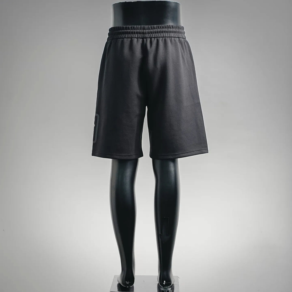Black knee-length shorts on legs, elastic waistband and relaxed wide-leg silhouette.