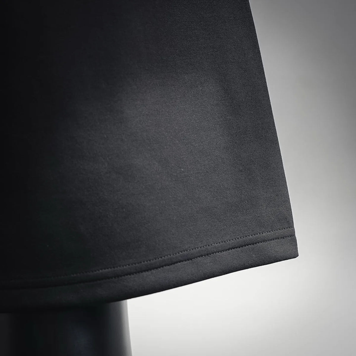 Black shorts hem with visible curved stitch line near bottom edge.
