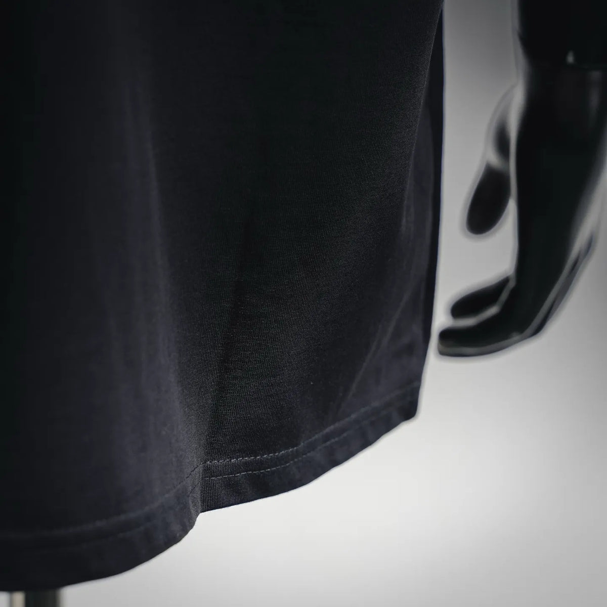 Black T-shirt hem with double-stitched seam and textured fabric.