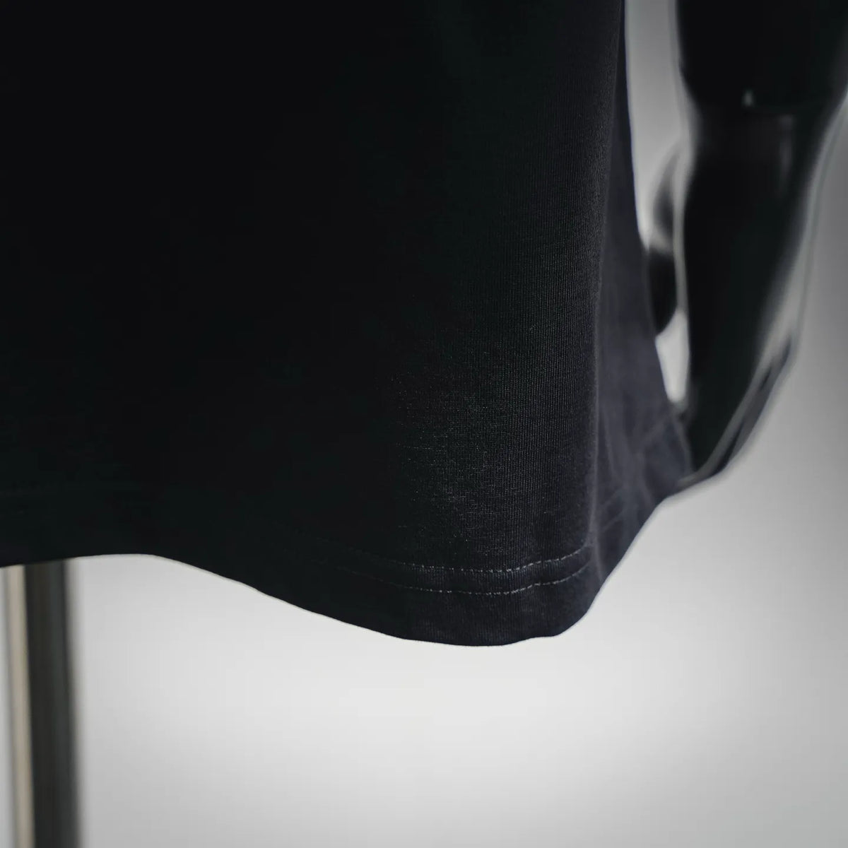 Black T-shirt hem with clean stitching detail.