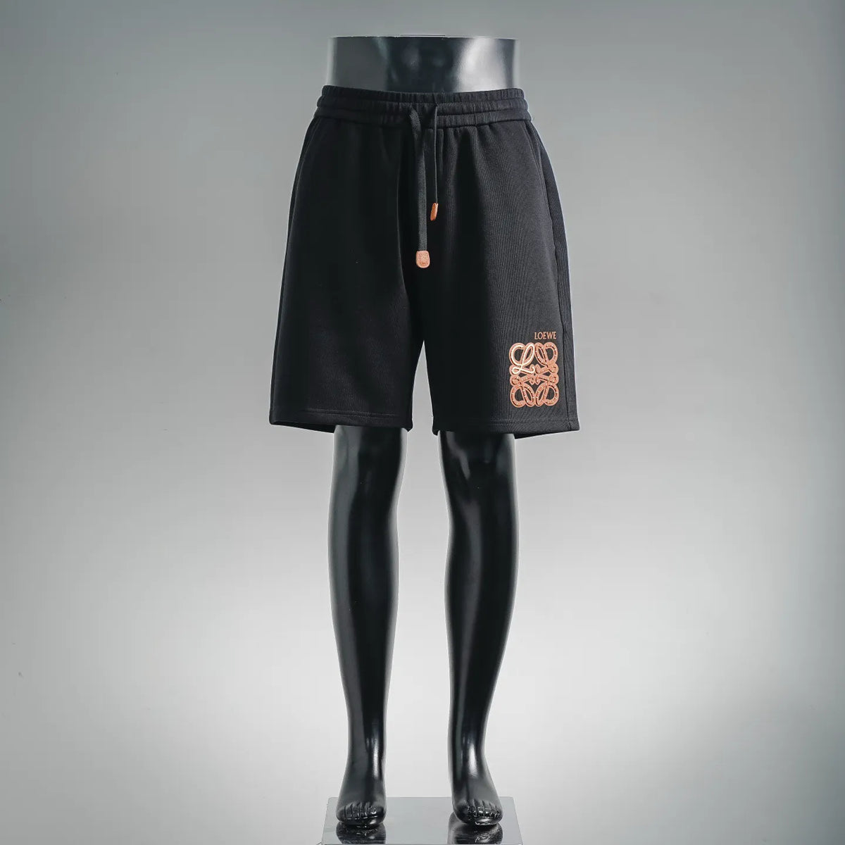Black drawstring shorts on mannequin, embroidered LOEWE logo patch at center front
