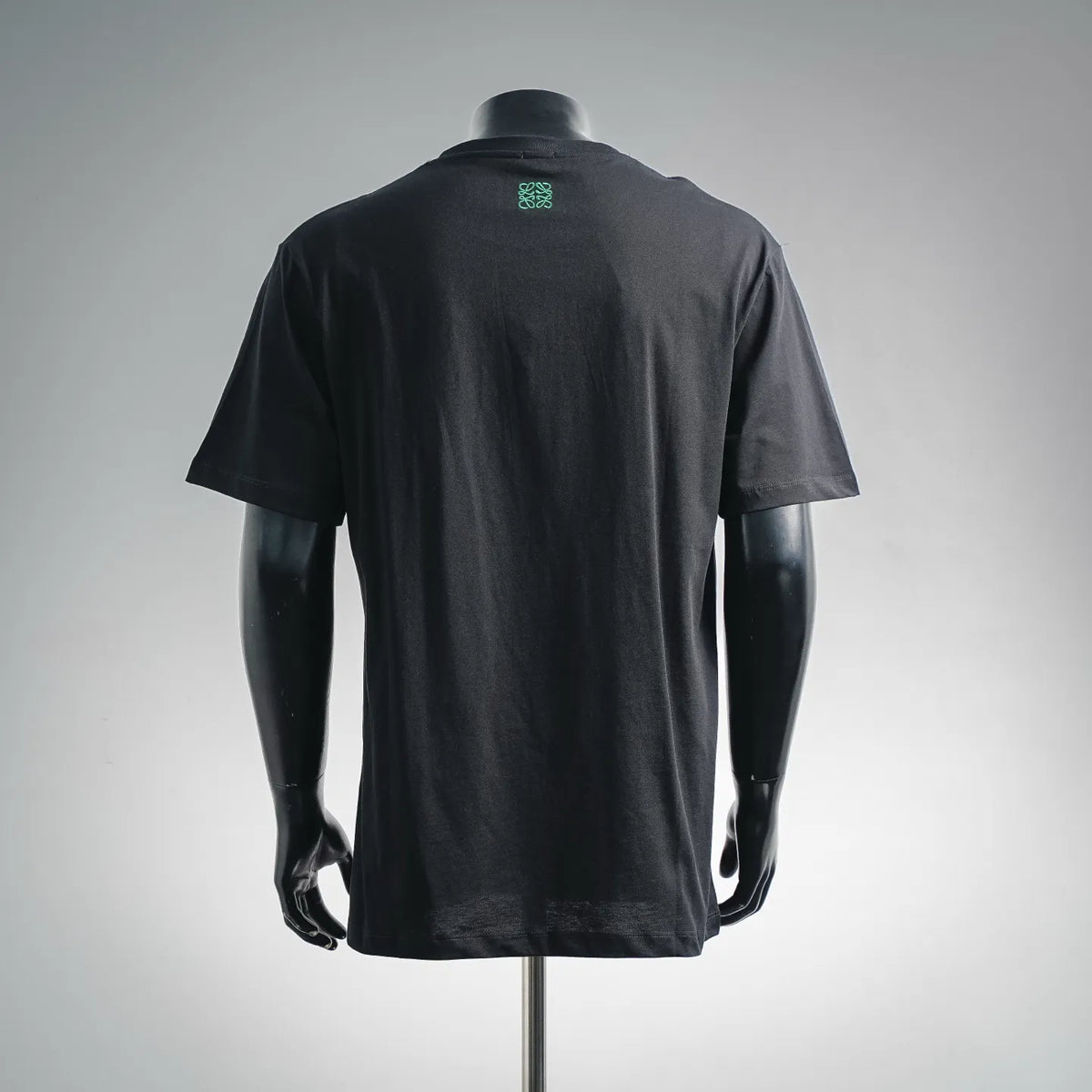 Black T-shirt with small green logo graphic on the back