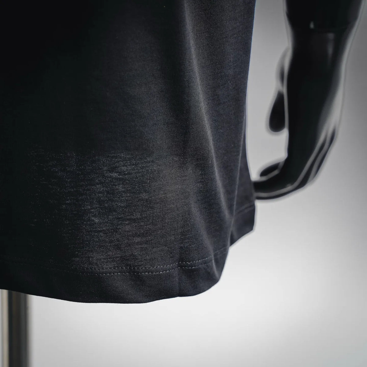 Black T-shirt lower front hem with visible stitching detail