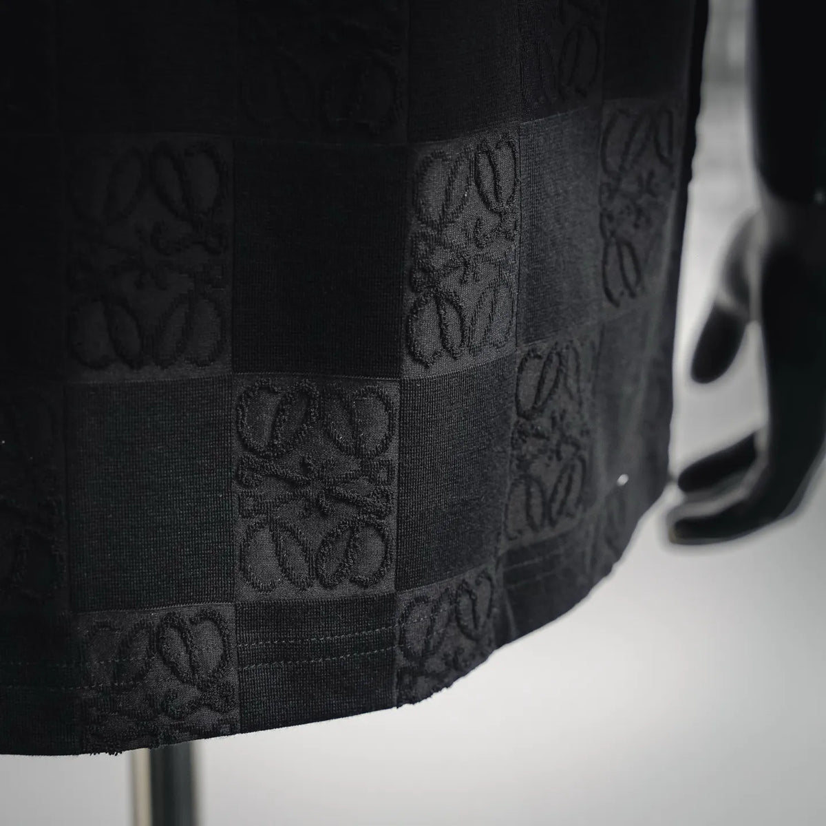 Black T-shirt fabric close-up with tonal embossed checkered monogram panels