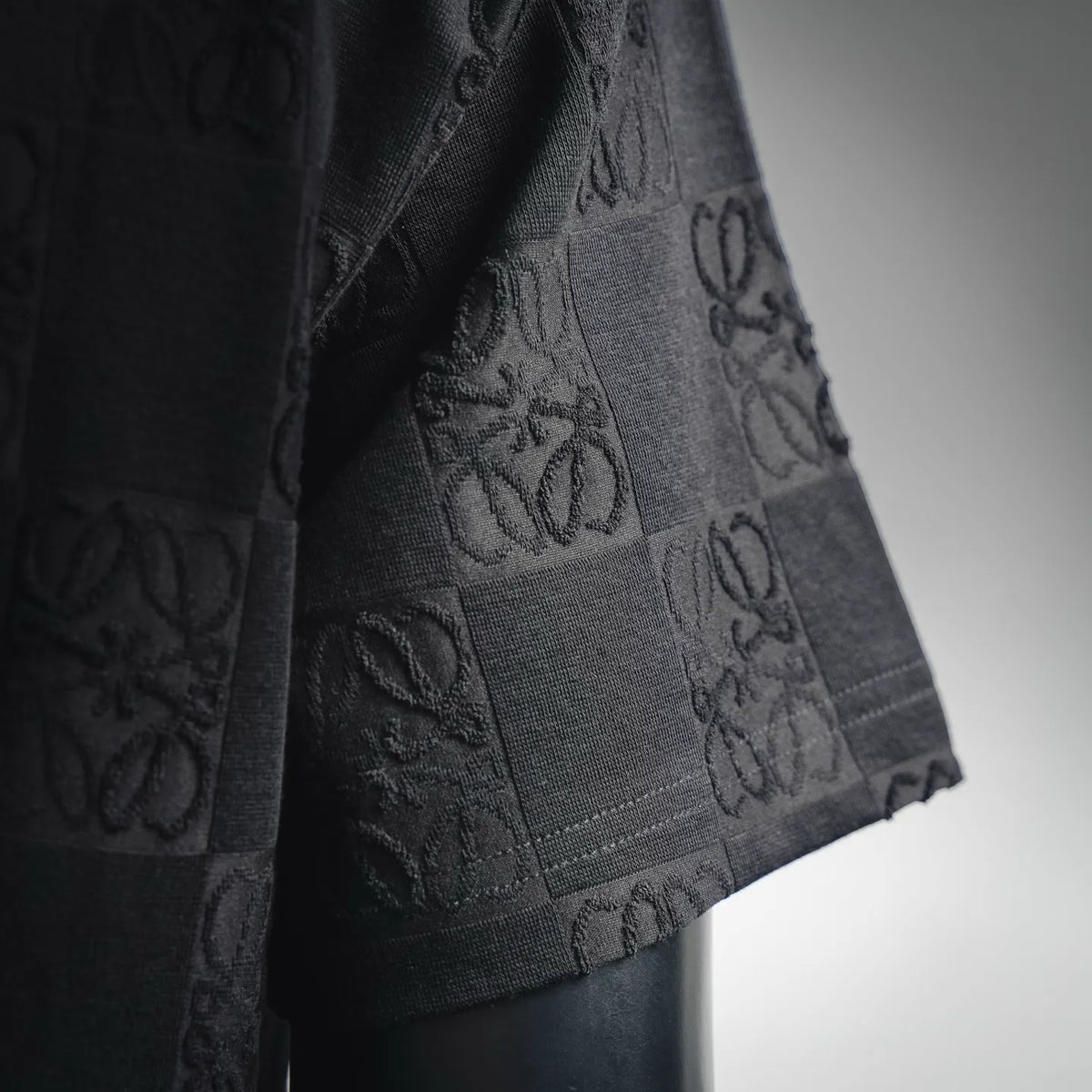 Black T-shirt side/hem close-up with tonal checkered monogram knit texture