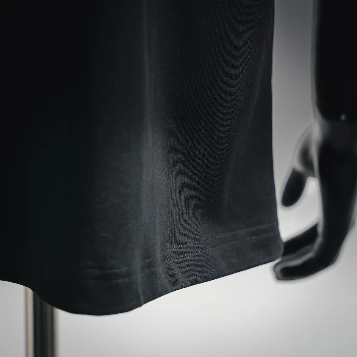 LOEWE short-sleeve T-shirt sleeve and hem close-up, dark fabric with stitched edge