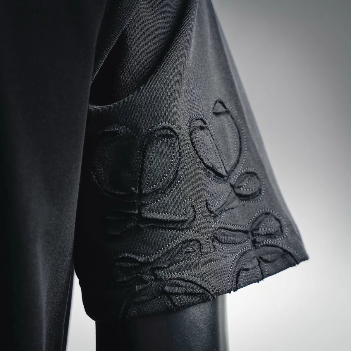 LOEWE short-sleeve T-shirt sleeve detail, embossed floral-style embroidery on dark fabric