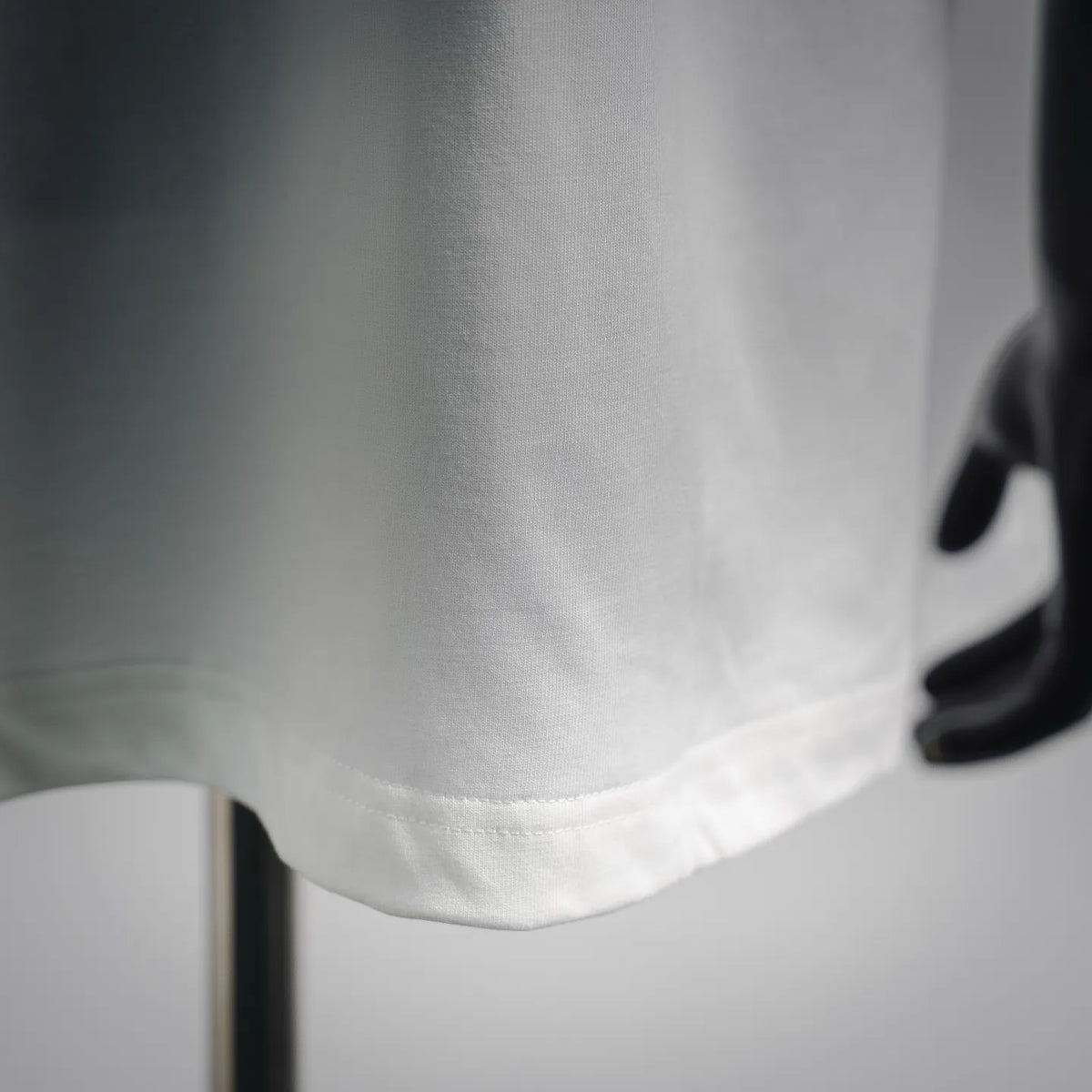White LOEWE T-shirt hem close-up, straight stitched edge.
