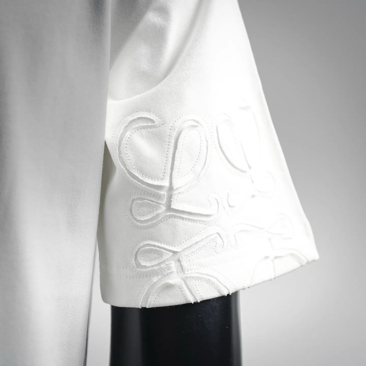 White LOEWE T-shirt sleeve with tonal embroidered logo, close-up.
